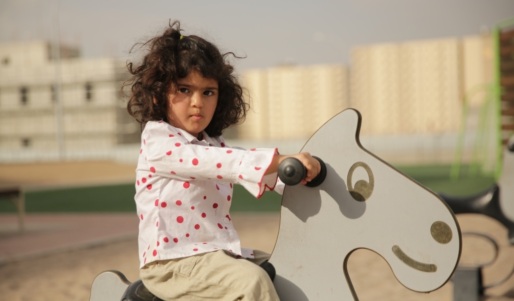 Маленькая девочка на деревянной лошади