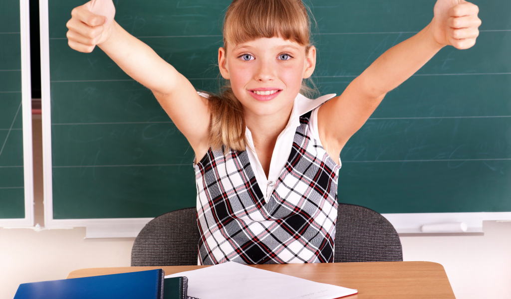 Маленькая девочка школьница в классе за партой 