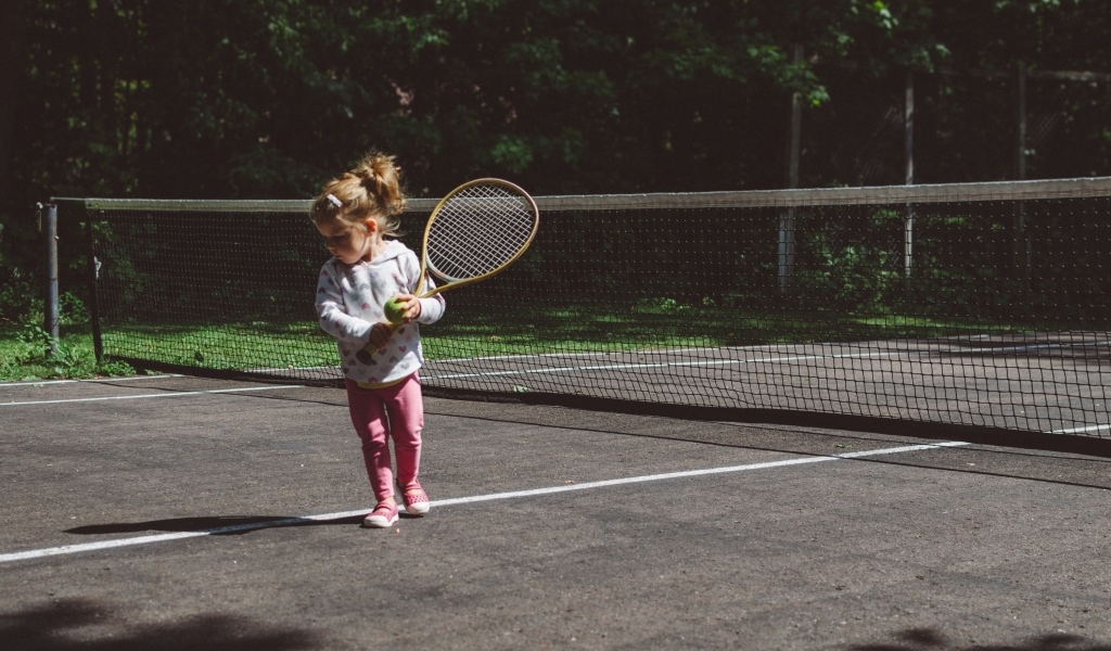 Маленькая девочка с ракеткой на поле