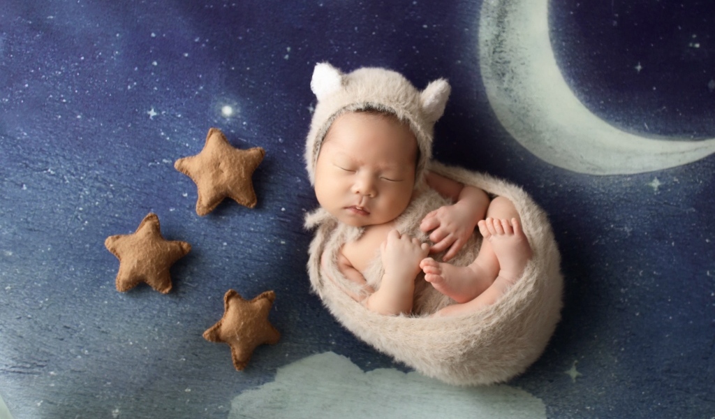 Маленький спящий грудной ребенок на синем покрывале