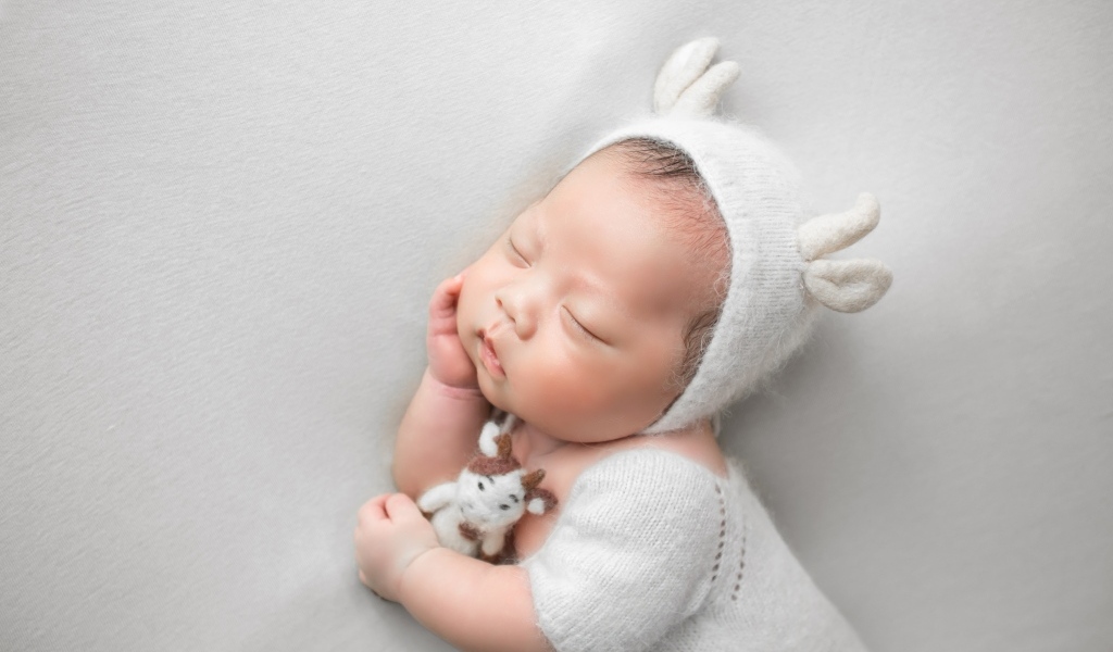 Маленький спящий малыш на сером фоне