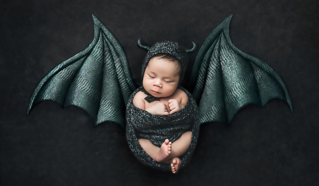 Маленький спящий ребенок с крыльями на Хэллоуин