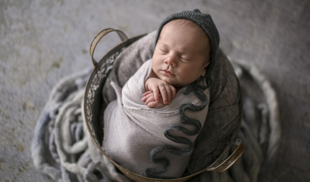 Маленький спящий новорожденный малыш в корзине