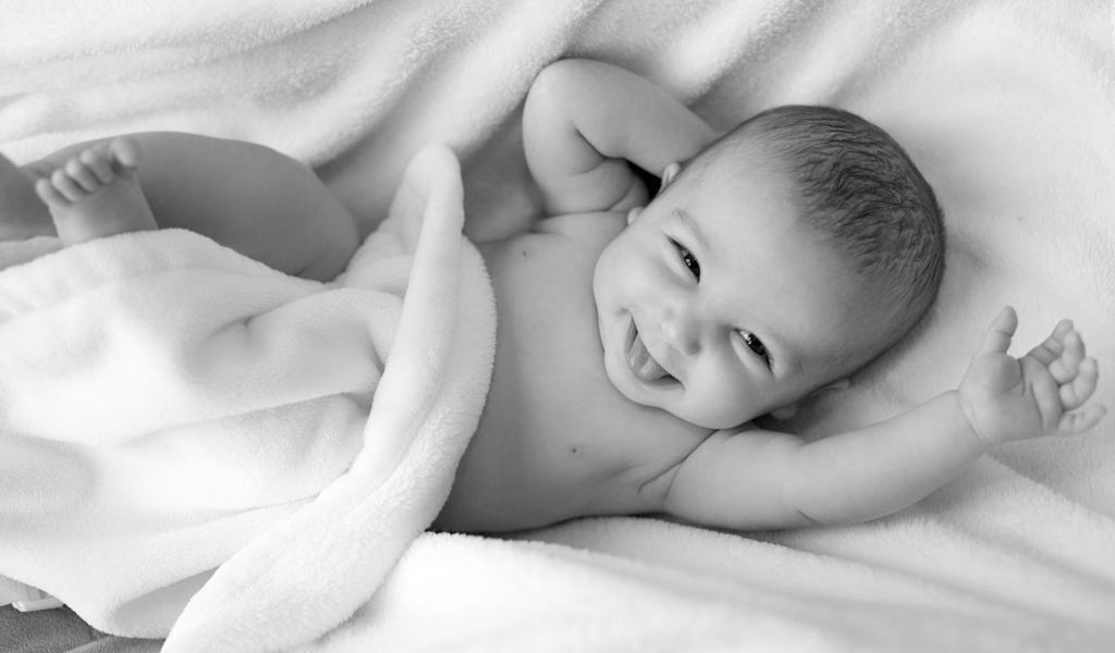 Маленький улыбающийся ребенок в белом покрывале