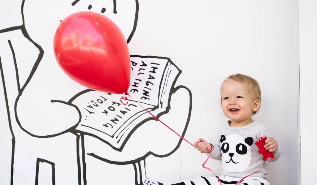 Маленький улыбающийся мальчик с шариком в руках