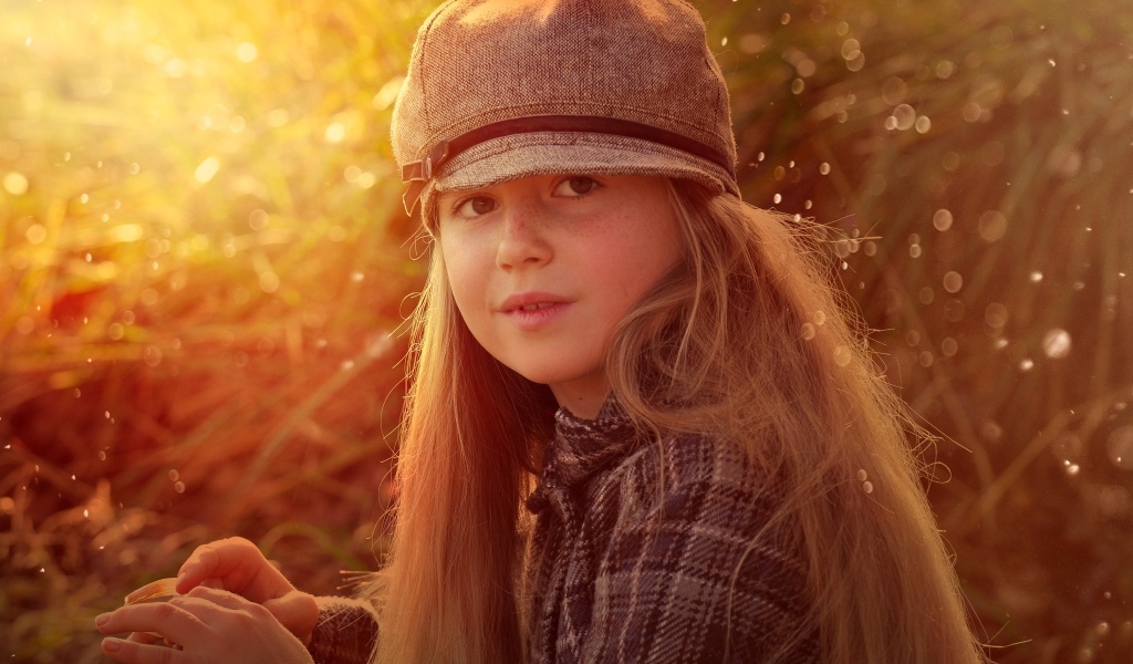 Длинноволосая девочка в кепке в лучах солнца