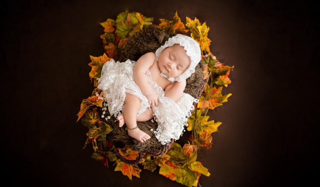 Новорожденная девочка в колыбели в белом костюме