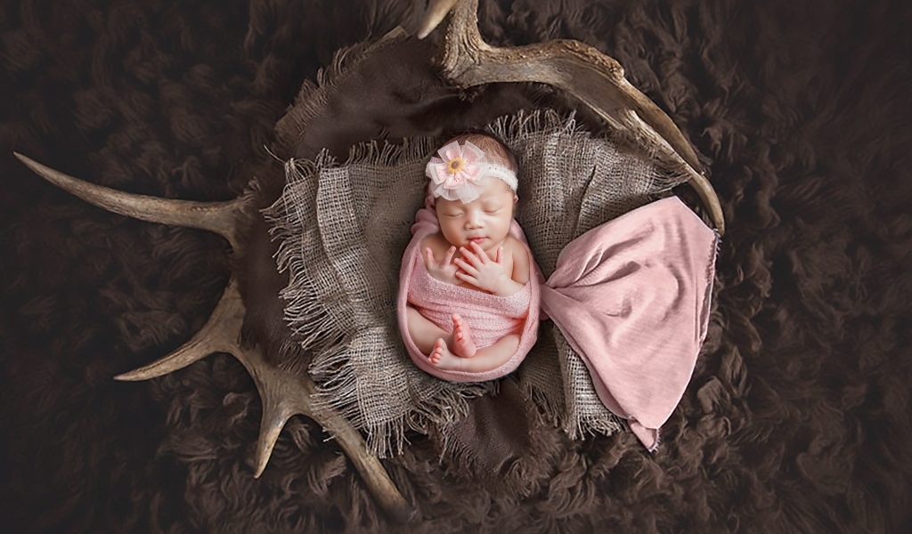 Новорожденная девочка на покрывале с рогами
