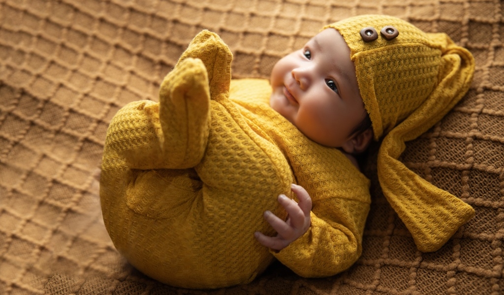 Новорожденный ребенок в желтом костюме 