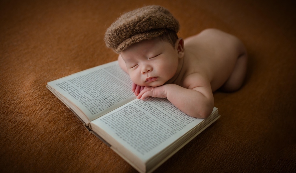 Новорожденный малыш спит на книге