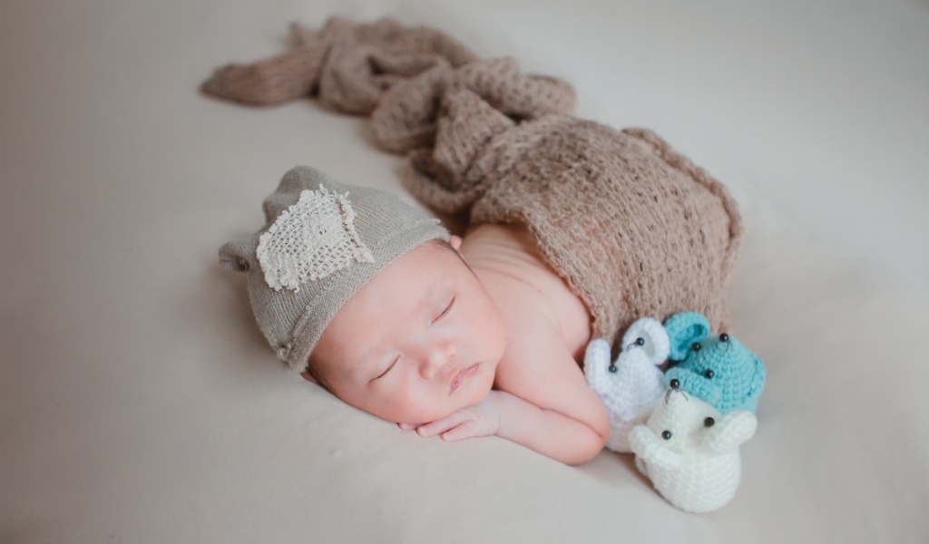 Новорожденный малыш спит на сером покрывале