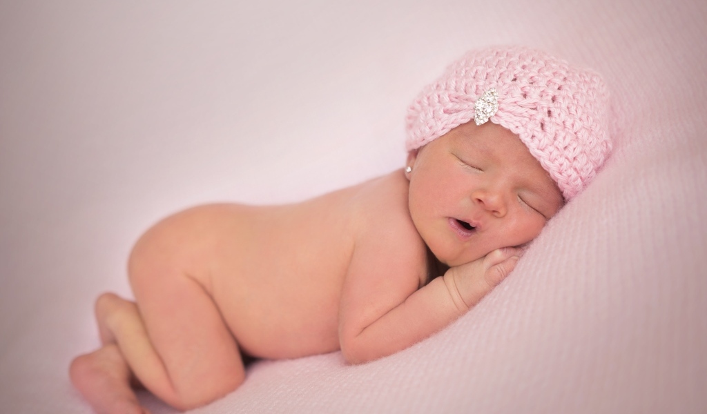 Розовая шапка на голове новорожденной девочки