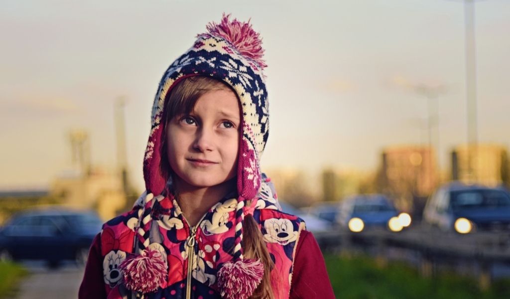 Грустная девочка в теплой шапке на улице