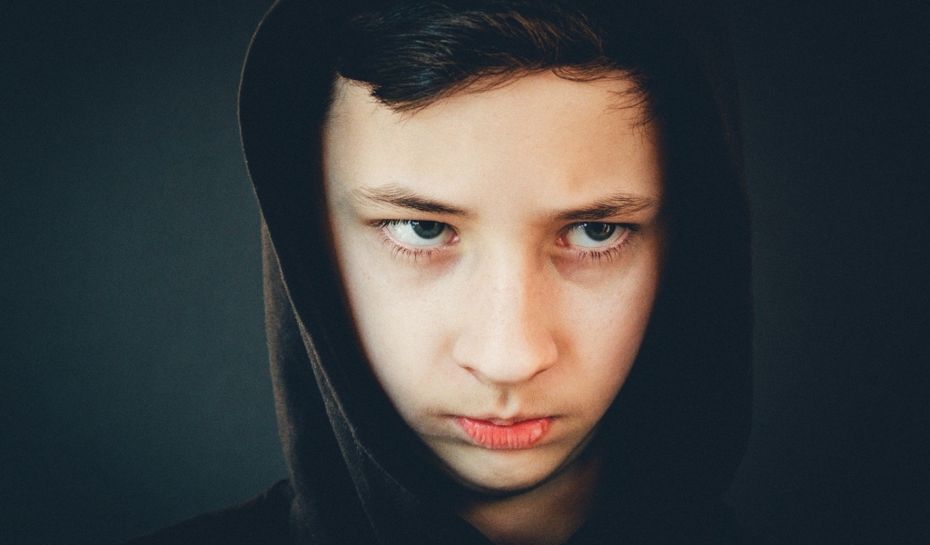 Серьезный мальчик в черном капюшоне