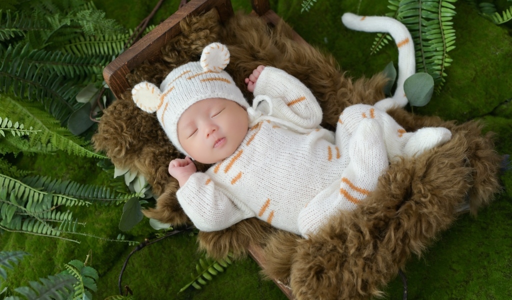 Спящий новорожденный ребенок в костюме тигренка