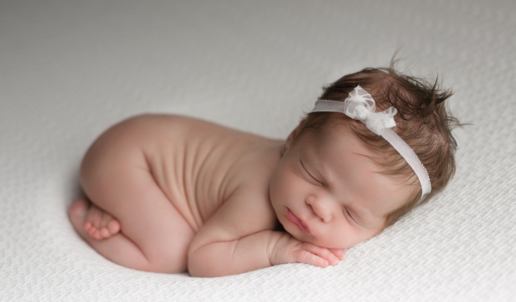 Спящая новорожденная девочка с ободком на голове