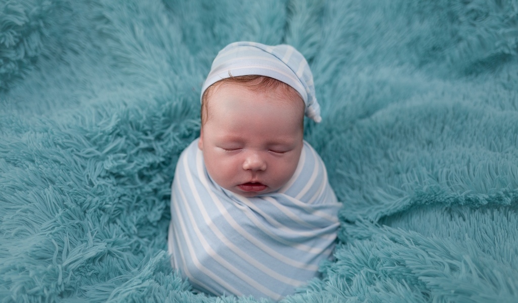 Спящий новорожденный малыш на голубом покрывале 