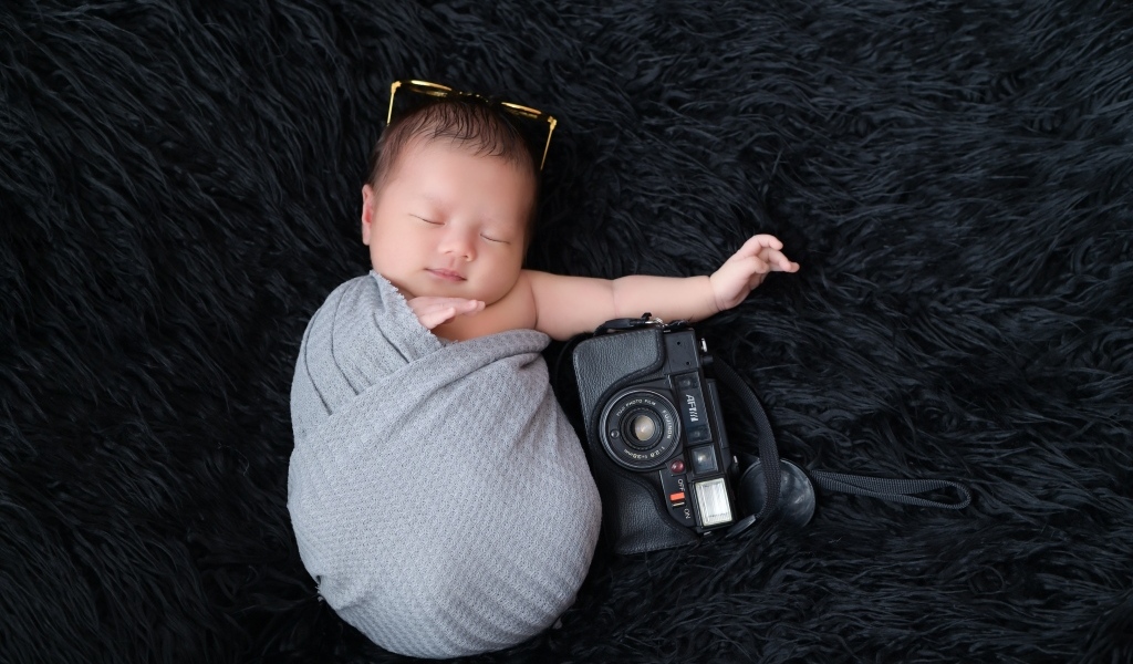Спящий новорожденный малыш с фотоаппаратом