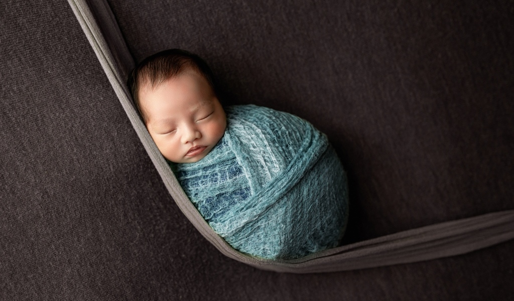 Маленький спящий ребенок завернут в покрывало