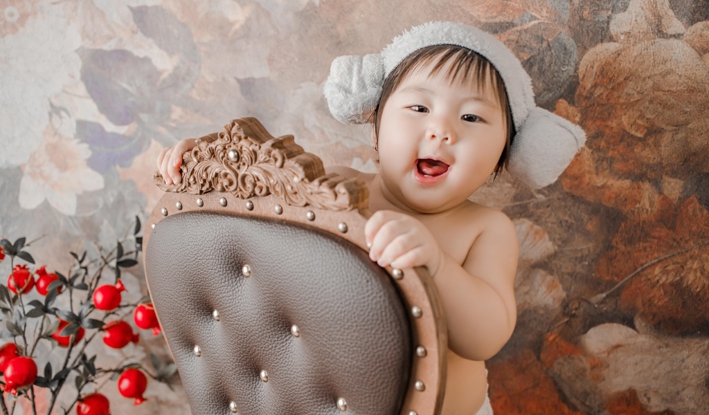 Улыбающийся ребенок азиат стоит у кресла