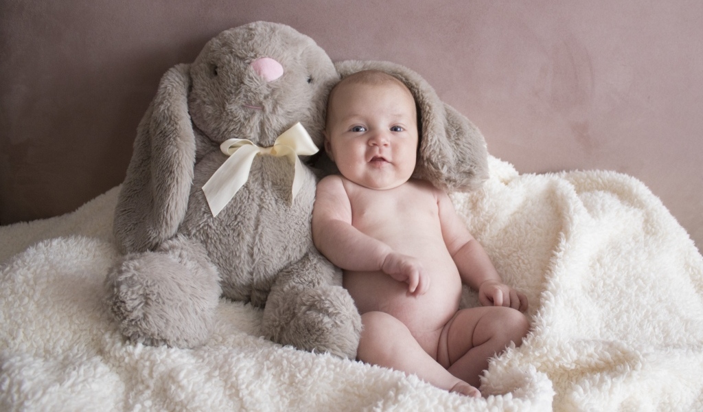 Улыбающийся малыш с игрушечным зайцем
