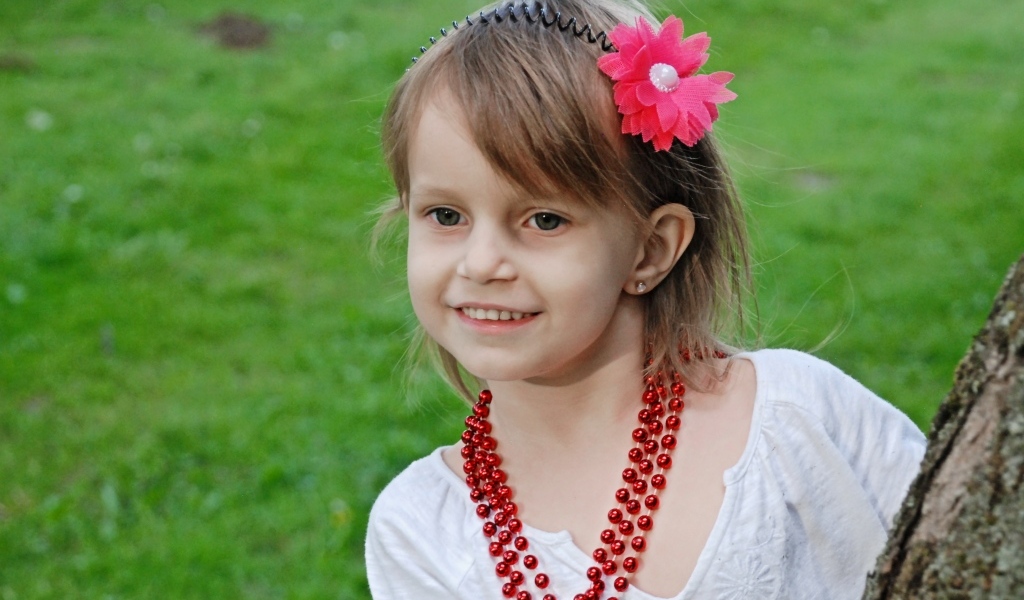 Улыбающаяся девочка стоит у дерева