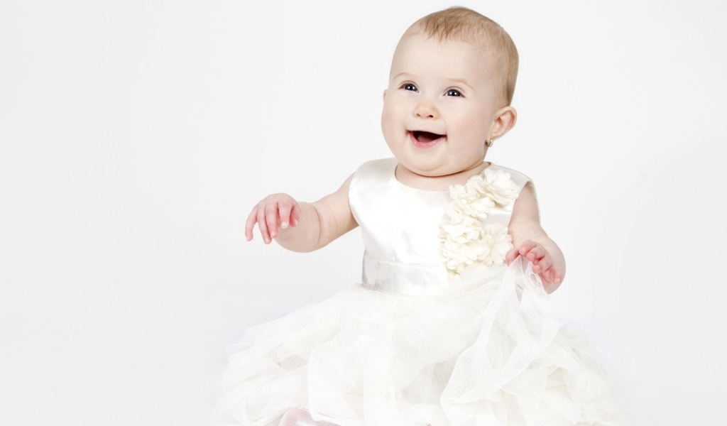 Улыбающаяся маленькая девочка в белом платье 