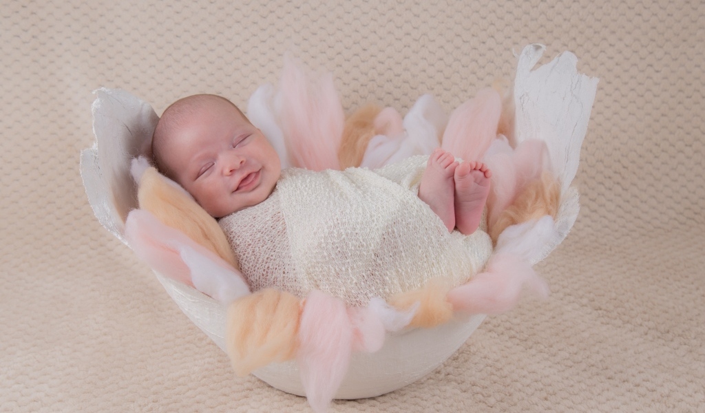 Улыбающийся спящий новорожденный малыш