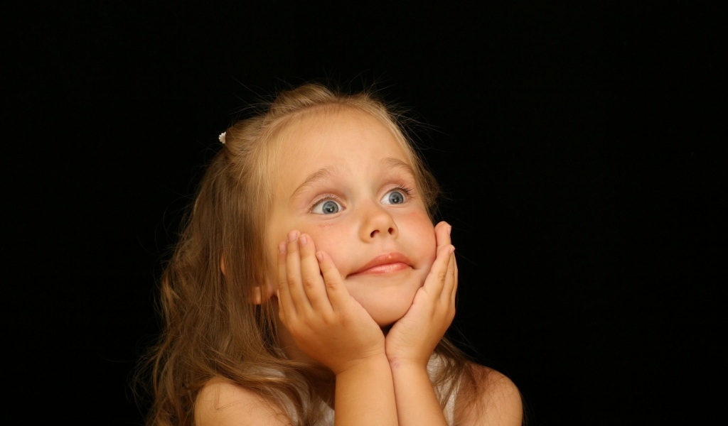 Удивленная маленькая девочка на черном фоне