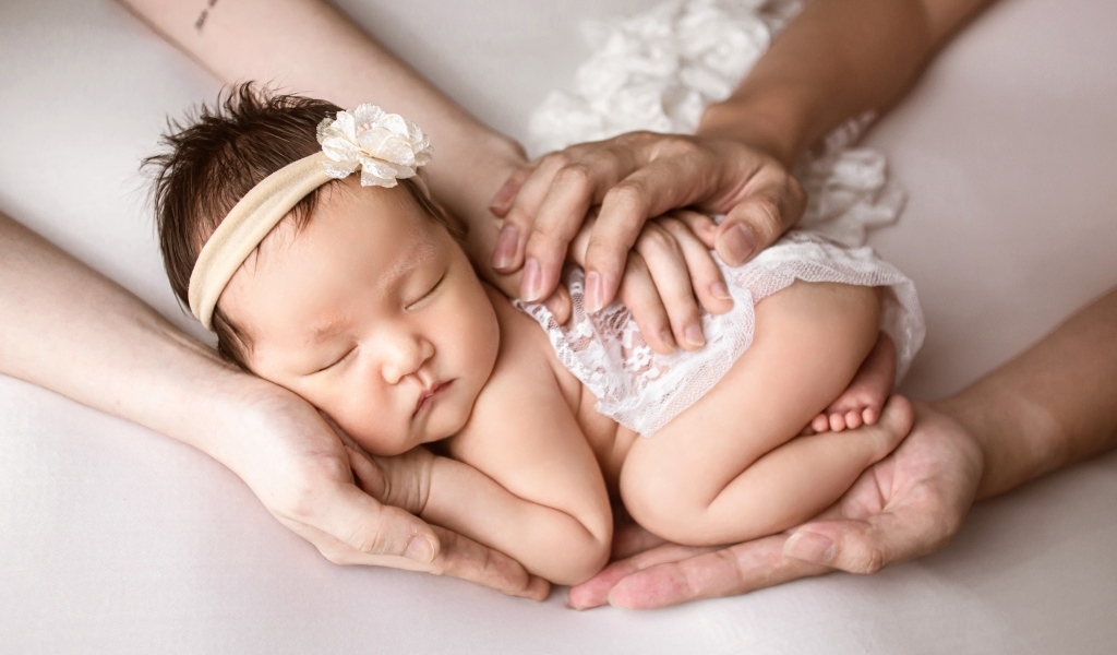 Руки родителей оберегают спящего малыша