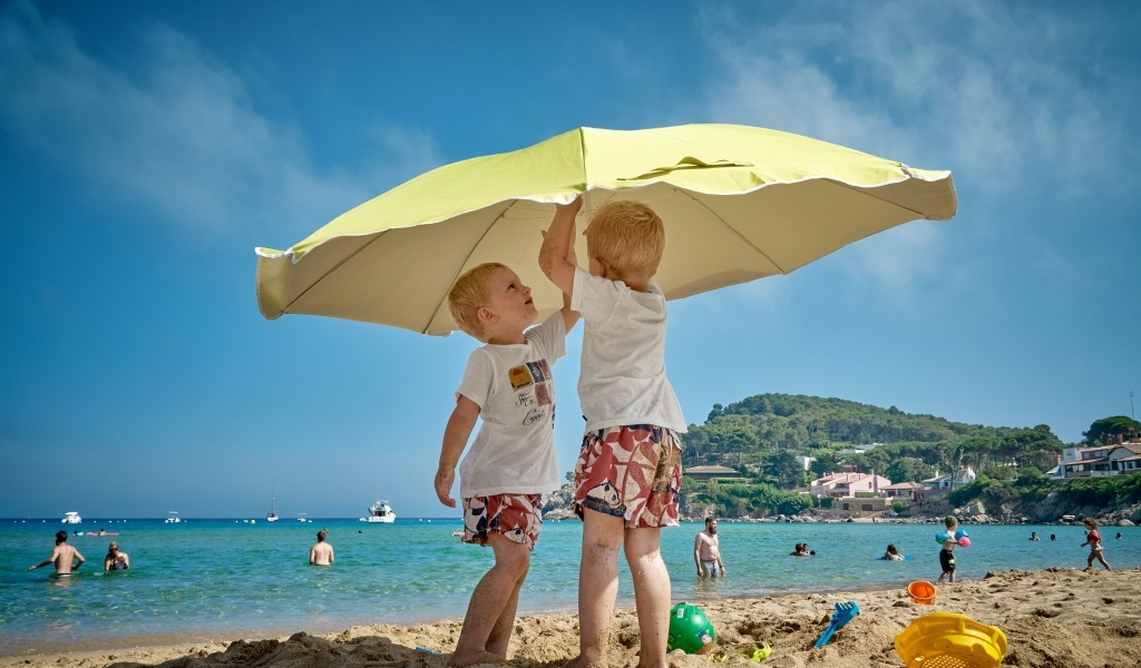 Два мальчика на пляже под зонтом