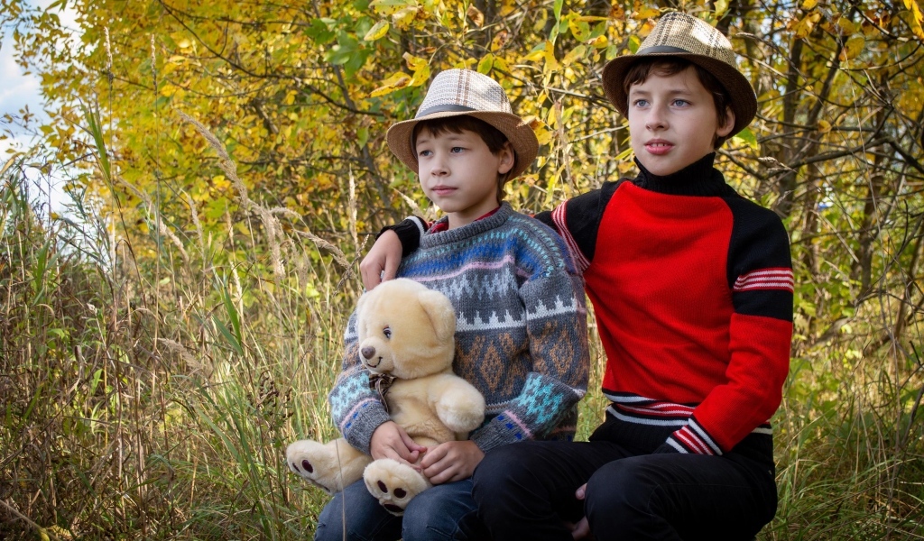 Два мальчика с игрушкой сидят у дерева