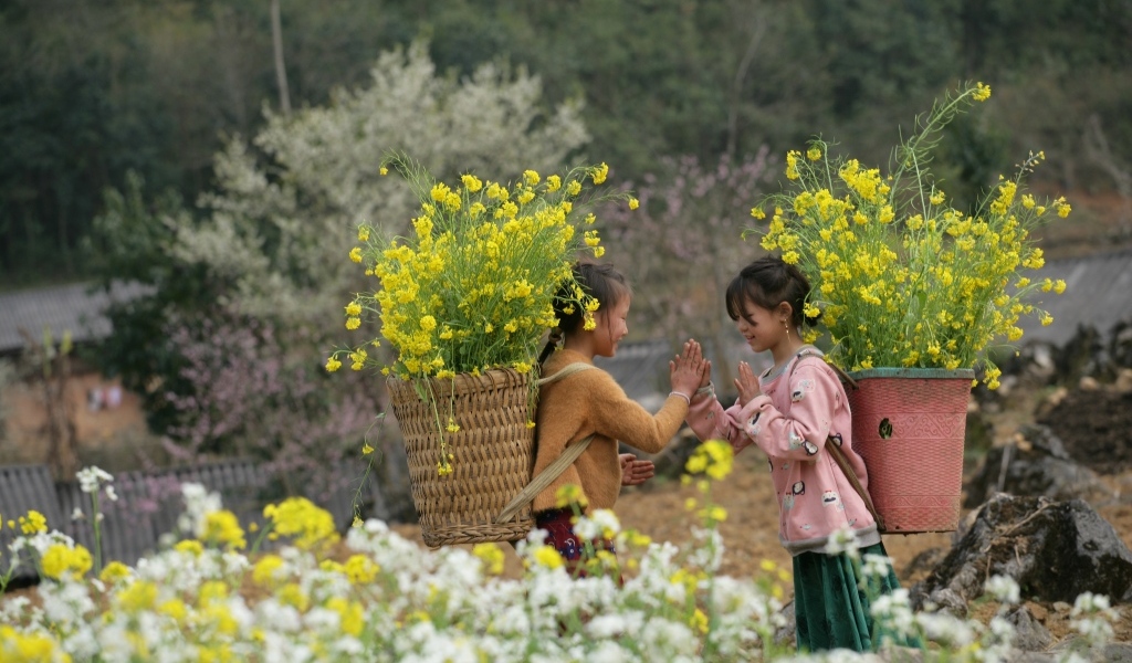 Две маленькие девочки азиатки с корзинами с желтыми цветами