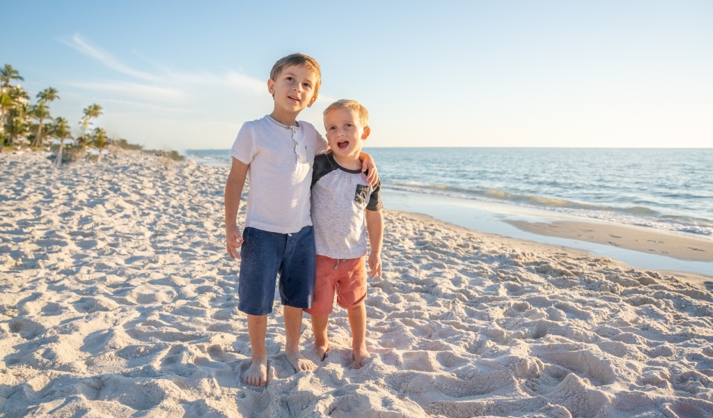 Два маленьких мальчика стоят на песке у моря