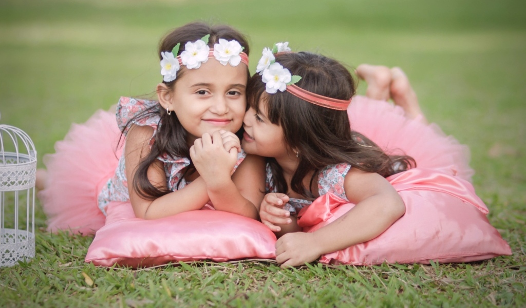 Две маленькие девочки лежат на подушках на траве