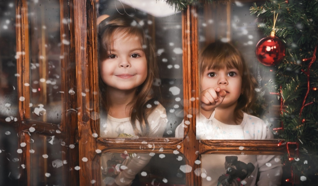 Две маленькие девочки сидят у окна на Рождество