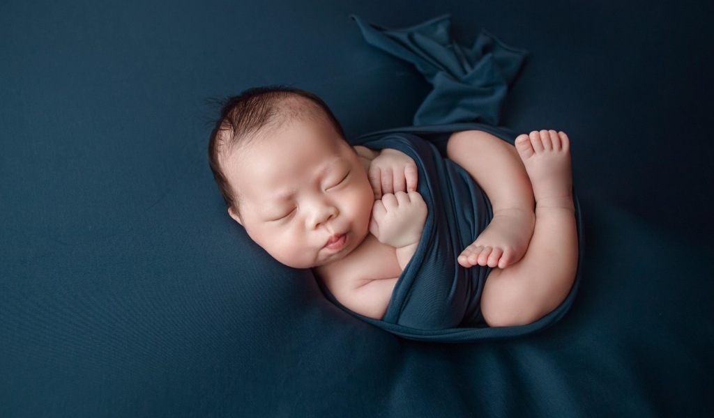 Новорожденный малыш в черном покрывале