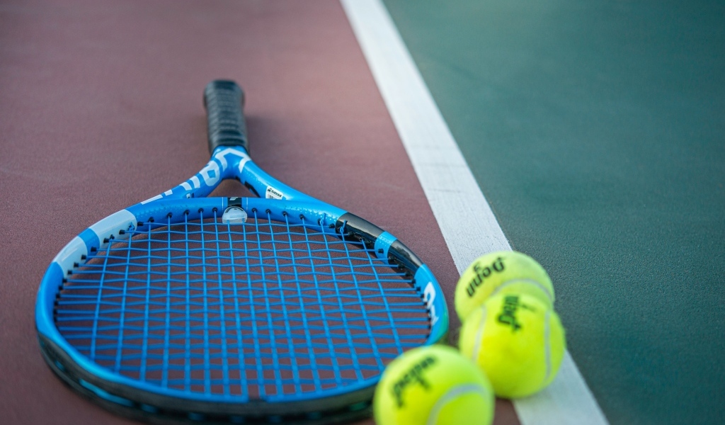 Ракетка и теннисные  мячи на корте