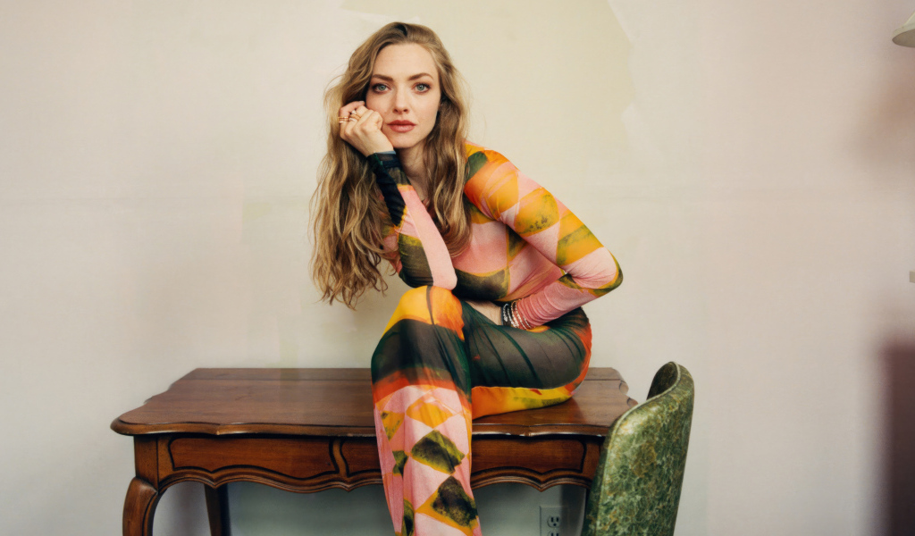 Актриса Аманда Сайфред в платье сидит на столе