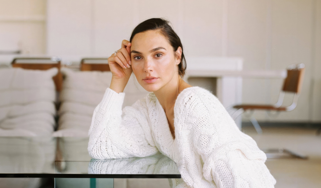 Актриса Галь Гадот в белом свитере за столом