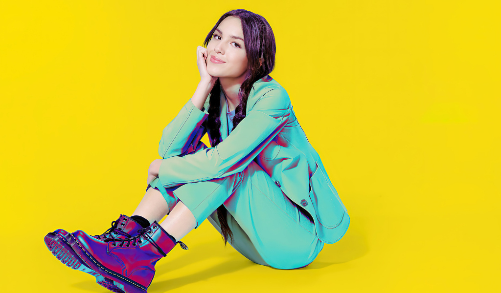 Актриса Оливия Родриго в костюме на желтом фоне