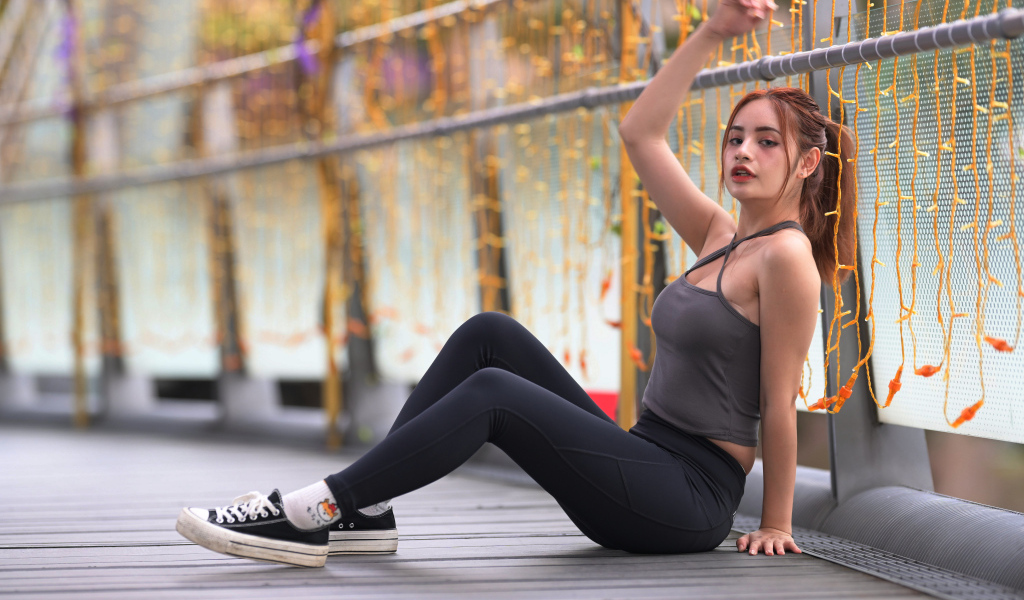 Спортивная девушка в костюме сидит на полу