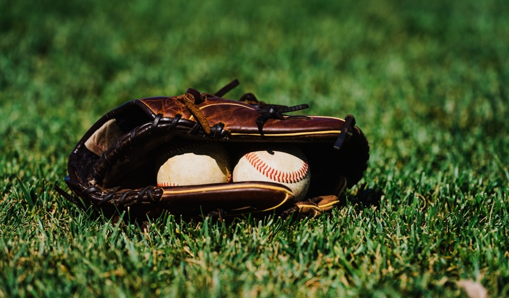 Бейсбольная перчатка и мячи на зеленой траве