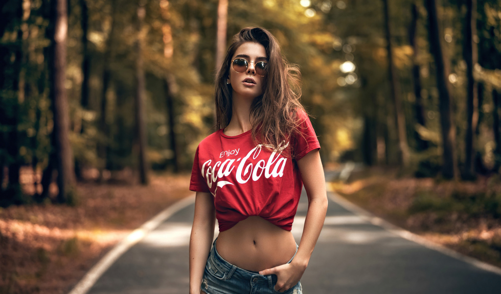 Красивая стройная девушка в футболке кока кола