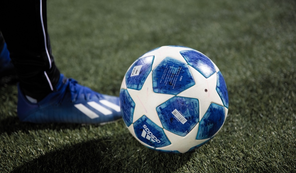 Синий футбольный мяч на зеленой траве поля