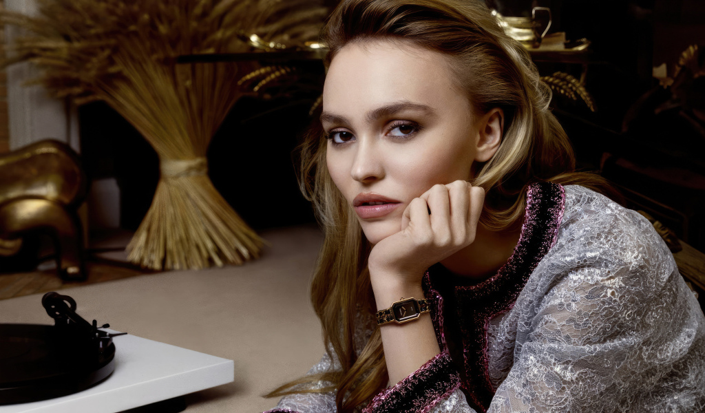 Милая девушка Лили-Роуз Депп сидит за столом