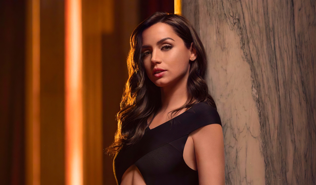 Длинноволосая актриса Ана де Армас стоит у стены