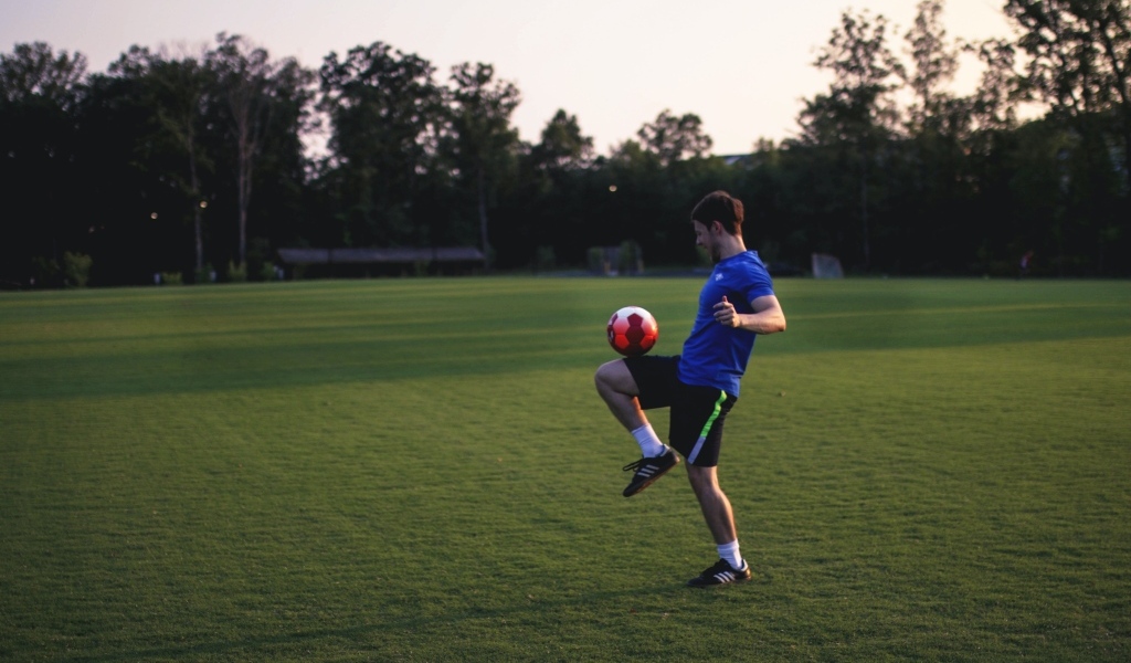 Мужчина футболист с мячом на поле