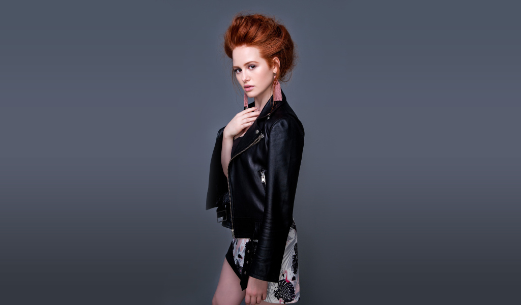 Рыжеволосая актриса Мэделин Петш в черной куртке на сером фоне