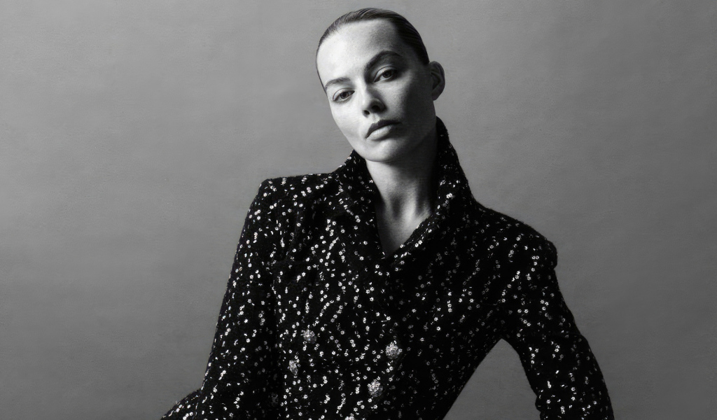 Грустная Марго Робби в блестящем пиджаке на сером фоне